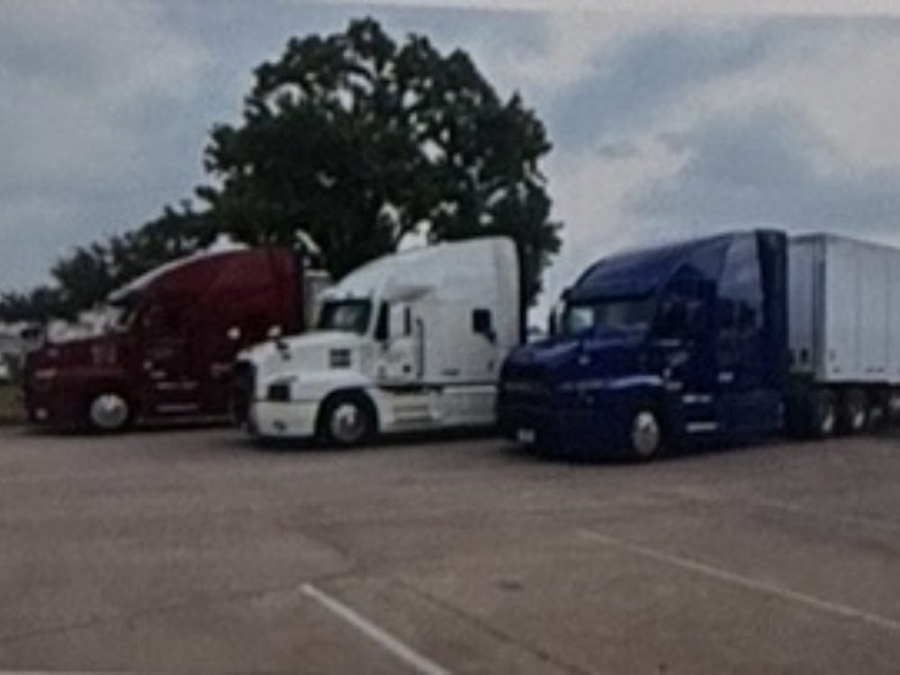 Red, white, and blue Edwards Transport Services Mack tractors parked side by side